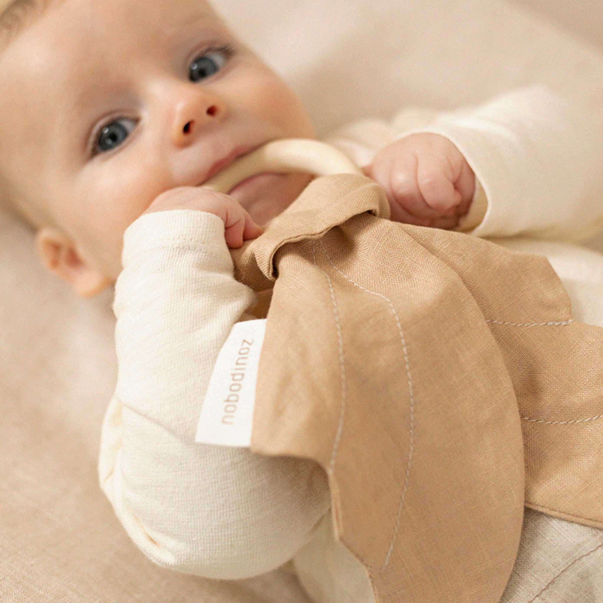 Baby Holding Nobodinoz Lin Francais Wings Teether Ring - Sand