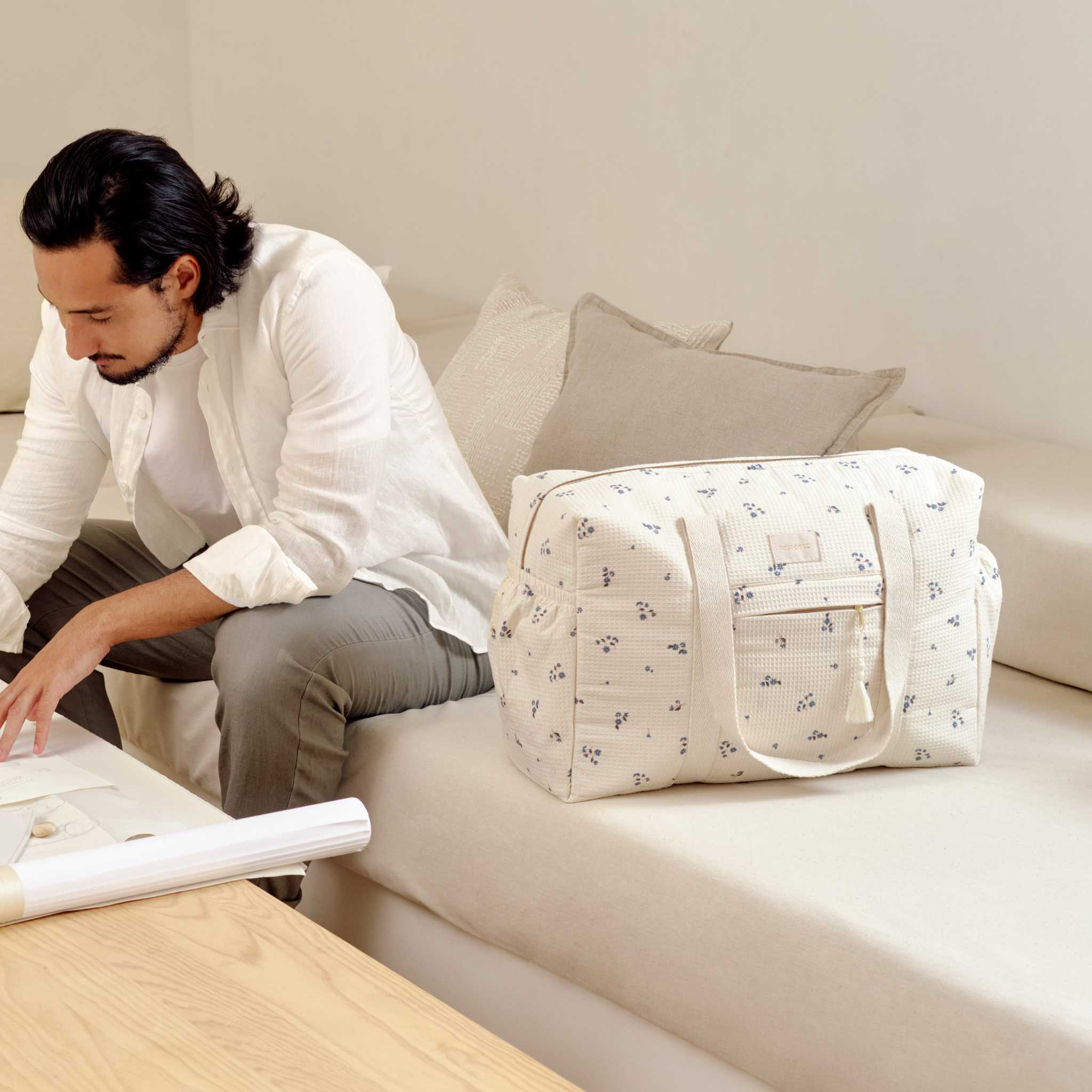 Nobodinoz Opera Changing Bag - Lilly Blue - With Man On Sofa