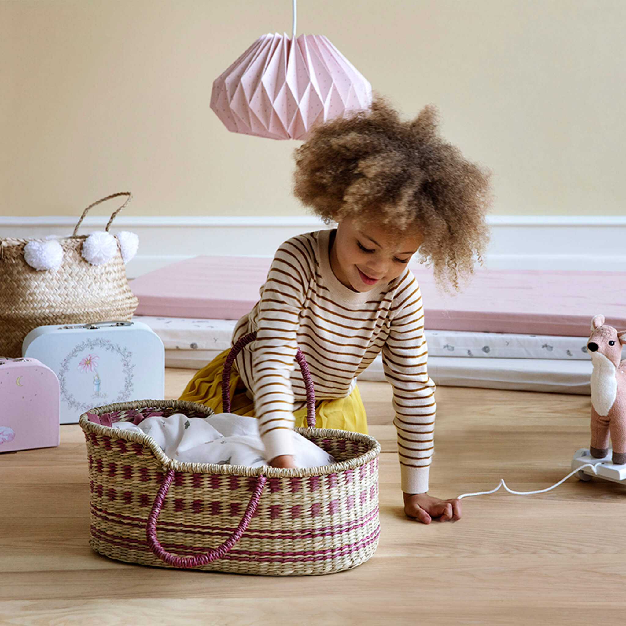 Girl Playing with Cam Cam Copenhagen Dolls Moses Basket in Berry