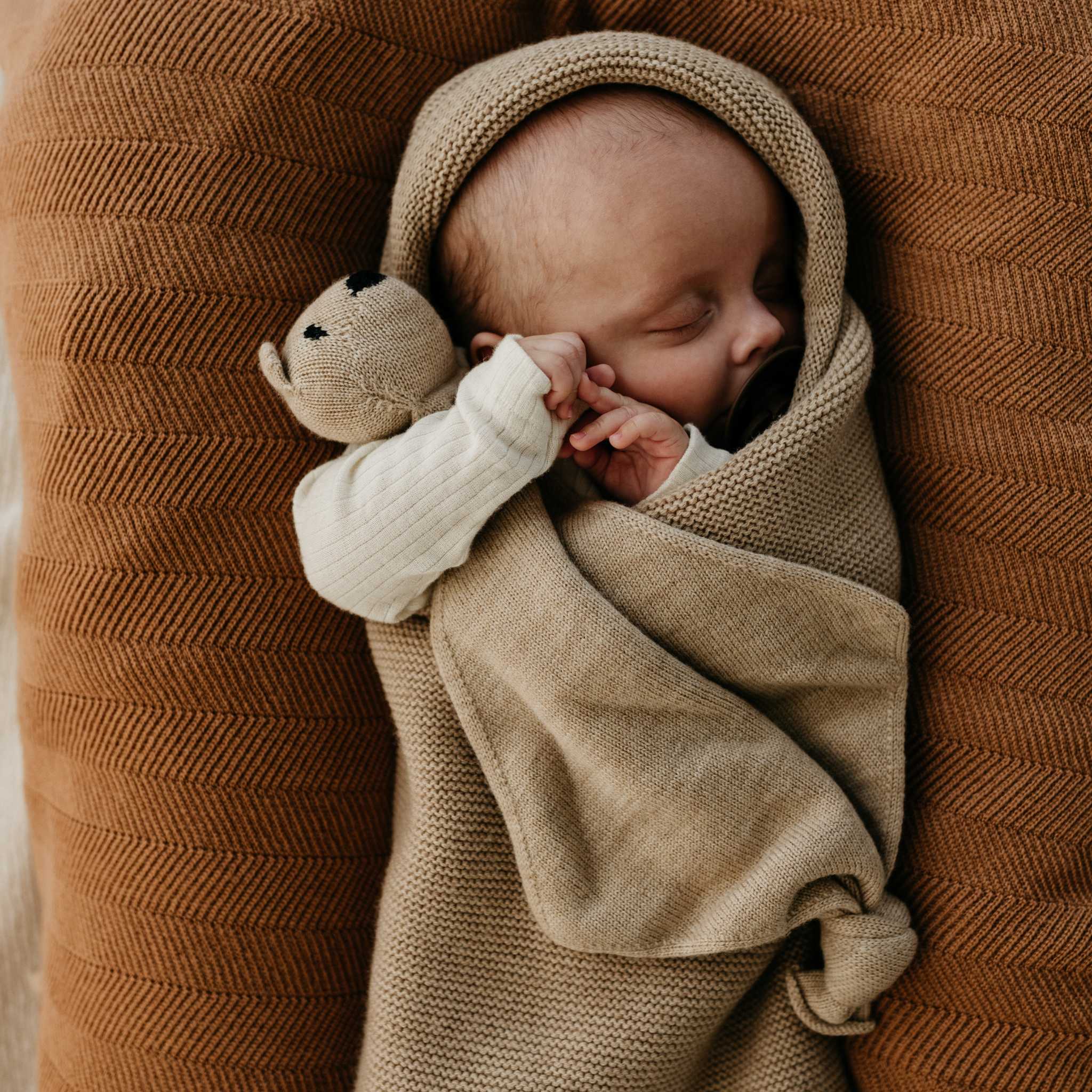 Baby Snuggled In Hvid Merino Wool Cocoon In Sand