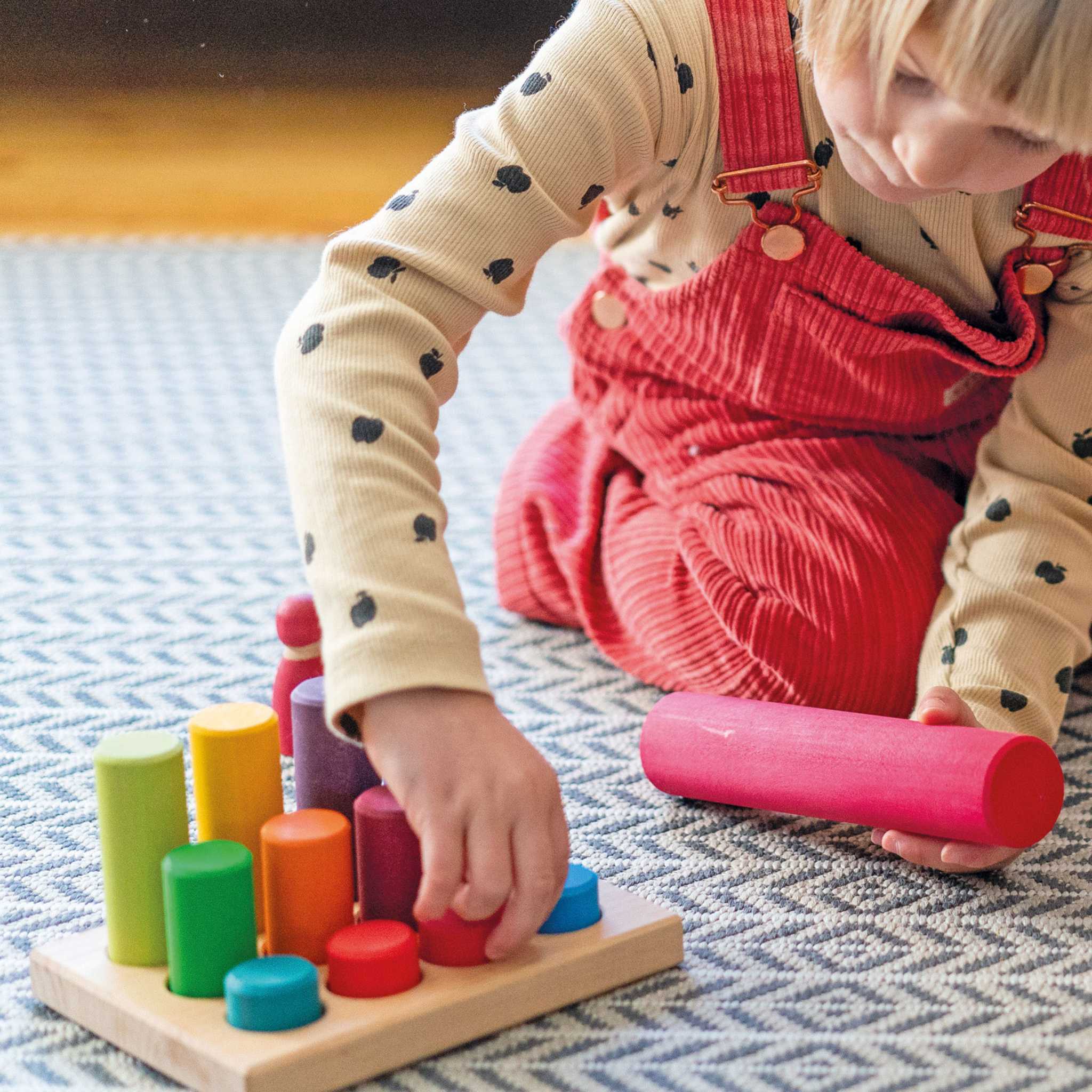 Child Playing with Grimm's Stacking Game Small Rainbow Rollers