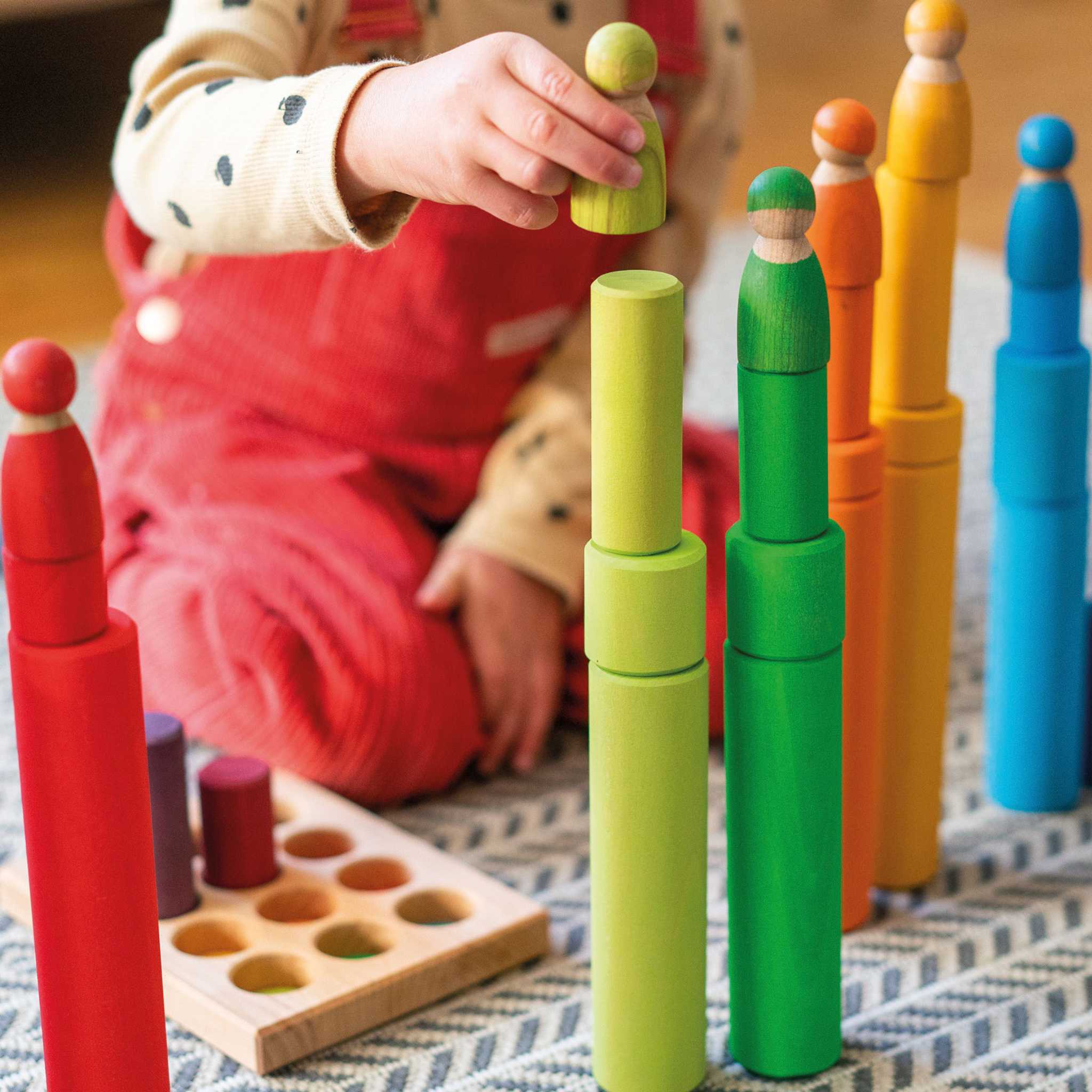 Child Playing With Grimm's Stacking Game Small Rainbow Rollers and Friends