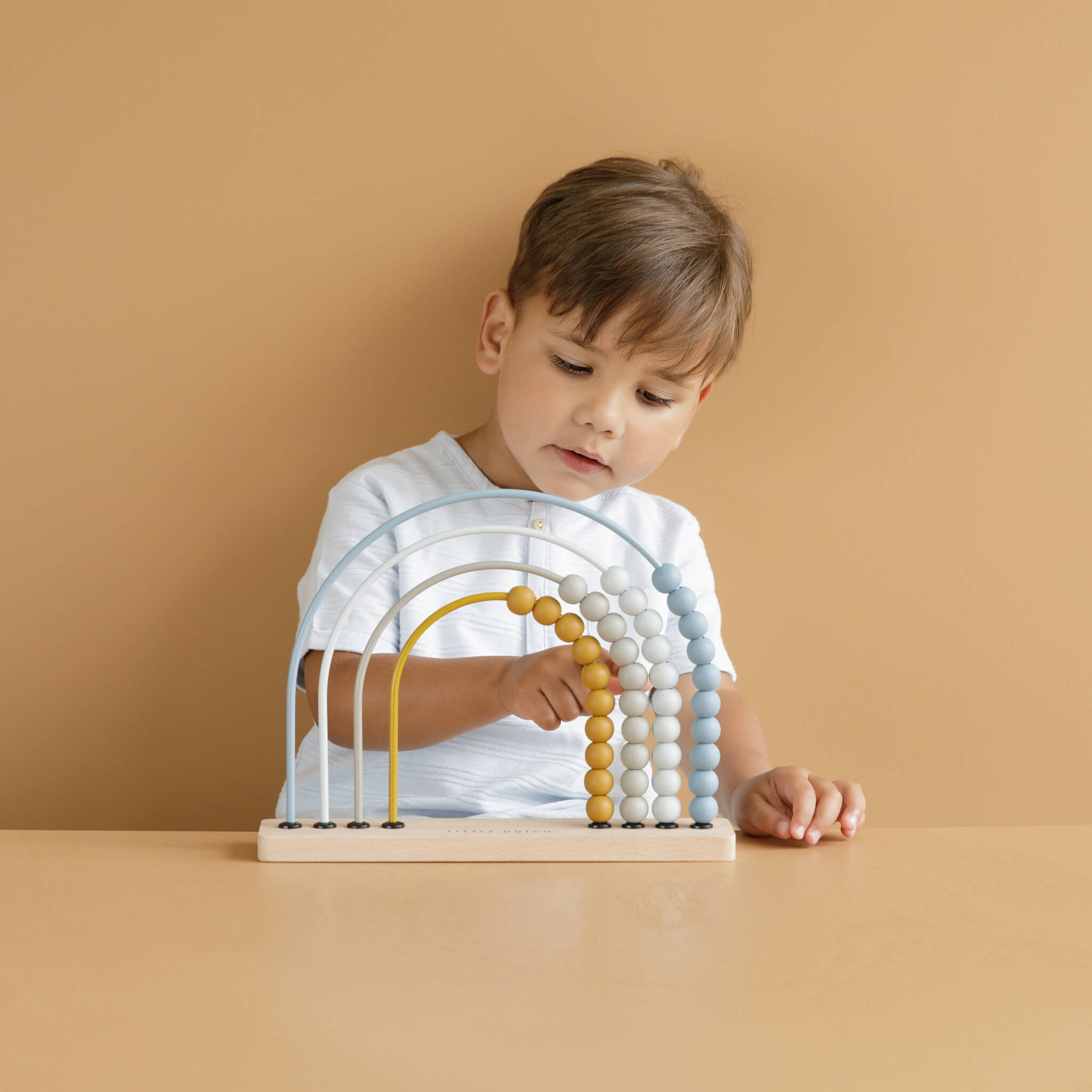 Boy Playing with Little Dutch Rainbow Abacus Toy in Blue