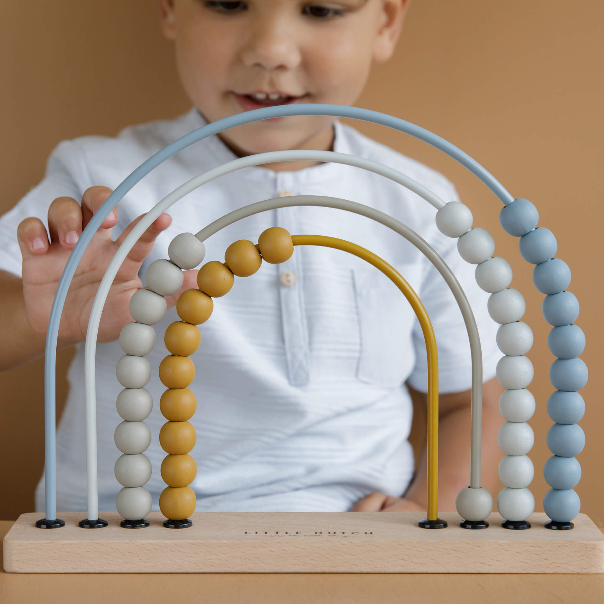 Boy Playing with Little Dutch Rainbow Abacus Toy in Blue