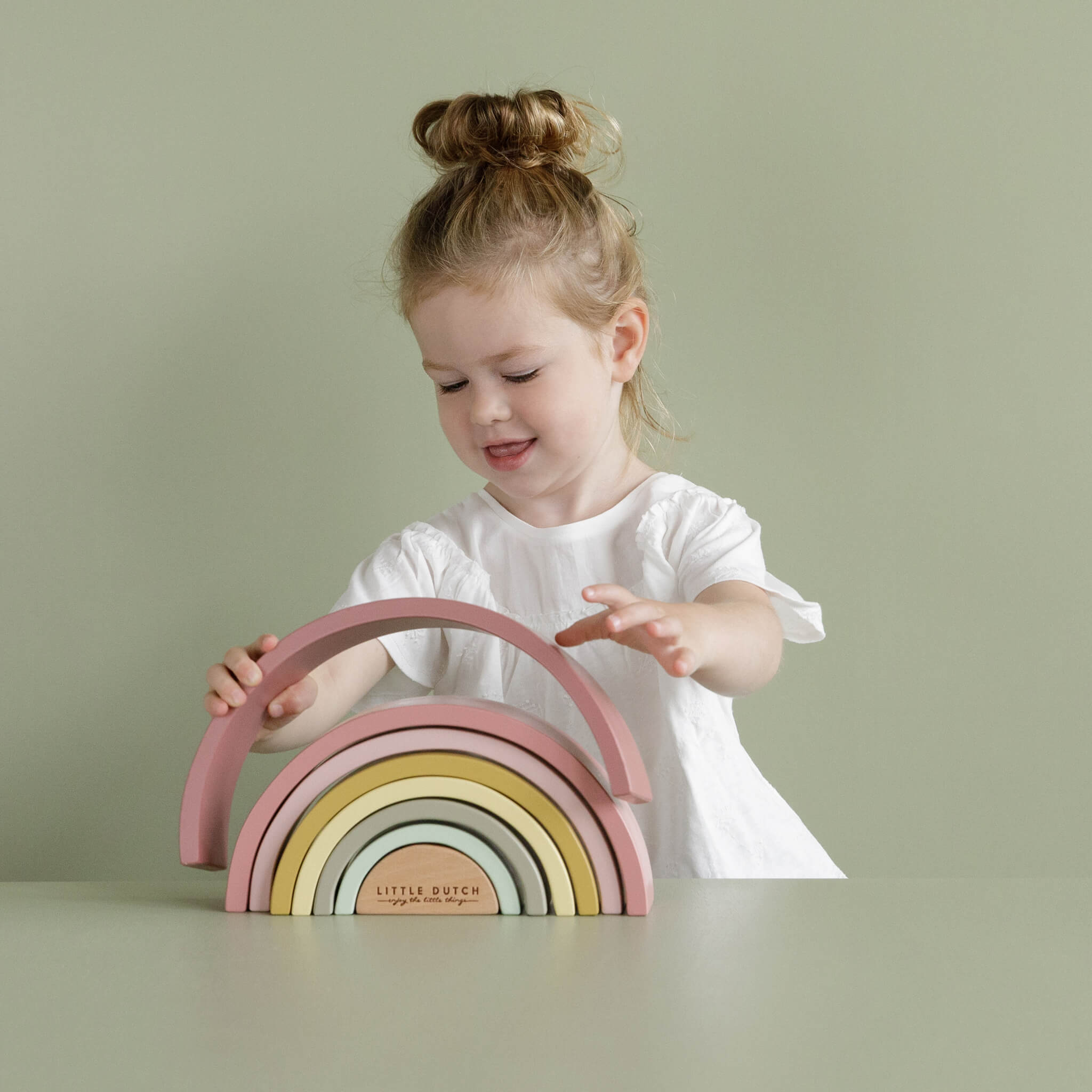 Girl Playing with Little Dutch Wooden Rainbow Stacker in Pink. Stacking Toy